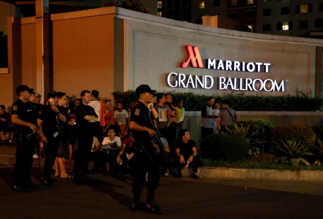 Policías montan una guardia cerca de unos empleados evacuados de un hotel en Pasay City, Filipinas, jun 2, 2017. Disparos y explosiones se escucharon el viernes en un complejo turístico en la capital de Filipinas, por lo que la policía desplegó agentes en el lugar, reportó la prensa local. REUTERS/Erik De Castro