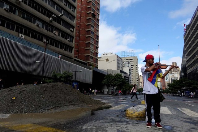 Venezuelan violinist Wuilly Arteaga plays the violin next to a pile of sand used by protesters to block the street during a protest against Venezuelan President Nicolas Maduro's government in Caracas, Venezuela July 18, 2017. REUTERS/Carlos Garcia Rawlins