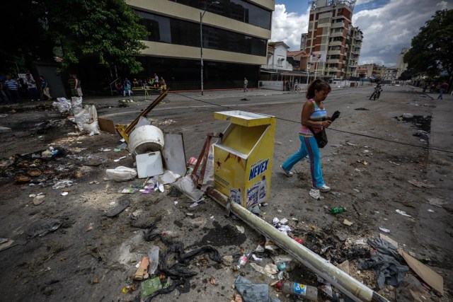 CAR105. CARACAS (VENEZUELA), 20/07/2017.- Una mujer camina frente a una barricada instalada por manifestantes para bloquear una calle hoy, jueves 20 de julio de 2017, en Caracas (Venezuela). Sectores enteros de Caracas permanecen hoy cerrados al tráfico en seguimiento del paro general de 24 horas convocado por la oposición contra el presidente, Nicolás Maduro, en una nueva acción de protesta antigubernamental que atrancó las comunicaciones y provocó el cierre de buena parte de los negocios. EFE/Cristian Hernández