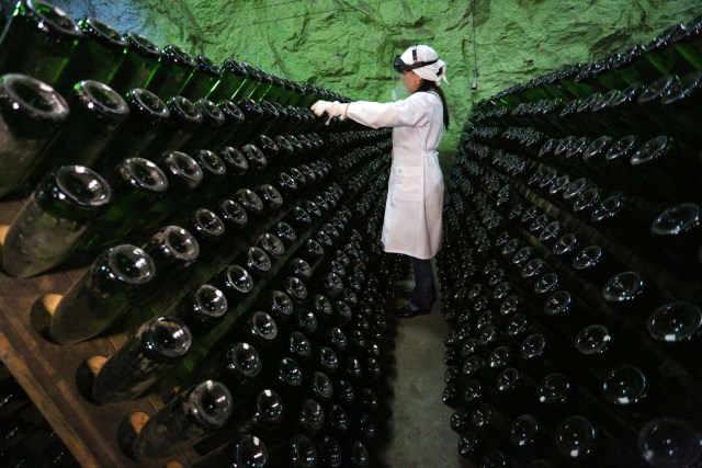 An employee turns bottles in the "Artwinery" winery firm in the eastern Ukrainian city of Bakhmut on July 12, 2017. The winery is located in a government-held town just two dozen kilometres (15 miles) from the frontline in Ukraine's low-level war, where the army and Russian-backed rebels continue to lob deadly artillery barrages at each other. The town spent around a month under rebel control in 2014, and in 2015 the frontline was so close that the town came under rebel shelling. But despite more than three years of fighting that has claimed some 10,000 lives, Nasyrov's employer, Artwinery, has never stopped production. / AFP PHOTO / Aleksey FILIPPOV