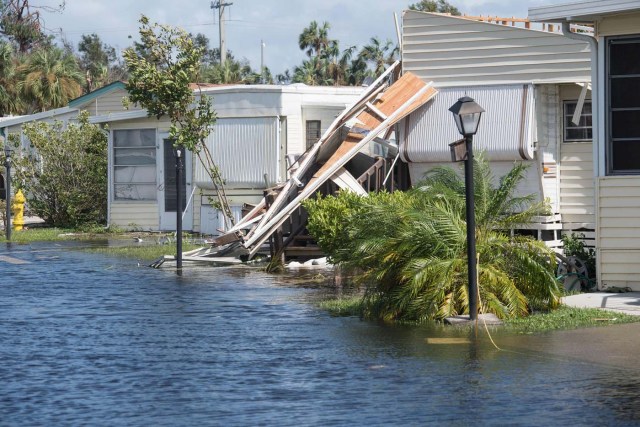 A damaged house is seen in a flooded street at the Enchanted Shores manufactured home park in Naples, Florida, on September 11, 2017 after Hurricane Irma hit Florida. / AFP PHOTO / NICHOLAS KAMM