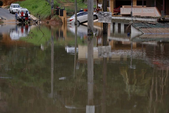 Local residents look at houses submerged by flood waters close to the dam of the Guajataca lake after the area was hit by Hurricane Maria in Guajataca, Puerto Rico September 23, 2017. REUTERS/Carlos Garcia Rawlins