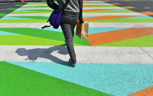 A pedestrian crosses a painted crosswalk by Venezuelan-born artist Carlos Cruz-Diez outside the Broad Museum in Los Angeles, California on September 14, 2017, where the painted crosswalks are a part of the Pacific Standard Time LA/LA Show, an exploration of Latino and Latin American Art in dialogue with Los Angeles. / AFP PHOTO / FREDERIC J. BROWN