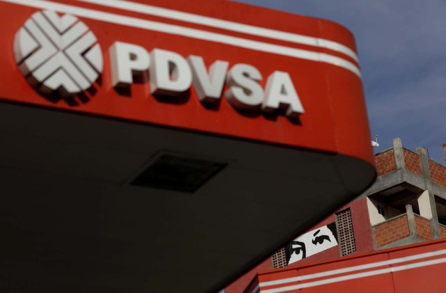 A painting depicting the eyes of Venezuela's late President Hugo Chavez, is pictured close to a corporate logo of the state oil company PDVSA at a gas station in Caracas, Venezuela, October 10, 2017.  Picture taken October 10, 2017. REUTERS/Ricardo Moraes