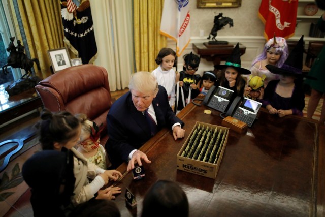 REFILE - CORRECTING GRAMMAR U.S. President Donald Trump gives out Halloween treats to children of members of press and White House staff in the Oval Office of the White House in Washington, U.S., October 27, 2017. REUTERS/Carlos Barria
