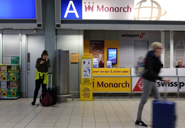 Passengers walk past the Monarch Airlines helpdesk at Luton airport on October 2, 2017. Britain's Monarch Airlines has gone into administration and all flights have been cancelled with 110,000 passengers currently abroad, the Civil Aviation Authority said Monday. / AFP PHOTO / Daniel LEAL-OLIVAS