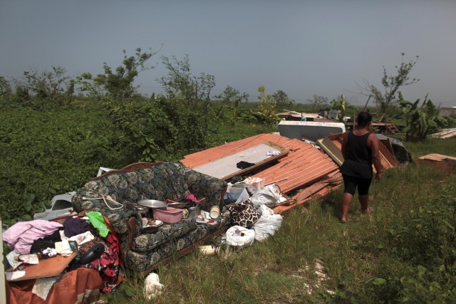 Cynthia Calderon walks past some furniture and other belongings she could salvage, after the island was hit by Hurricane Maria in September, in Toa Alta, Puerto Rico October 19, 2017. REUTERS/Alvin Baez