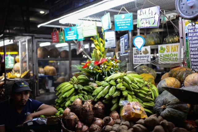 A fruits and vegetables seller waits for customers at the municipal market of Chacao in Caracas on November 2, 2017. This week, Venezuelan President Nicolas Maduro introduced a new bank note of 100,000 Bolivars - five times the current largest denomination - and announced a 30 percent minimum wage hike. / AFP PHOTO / FEDERICO PARRA