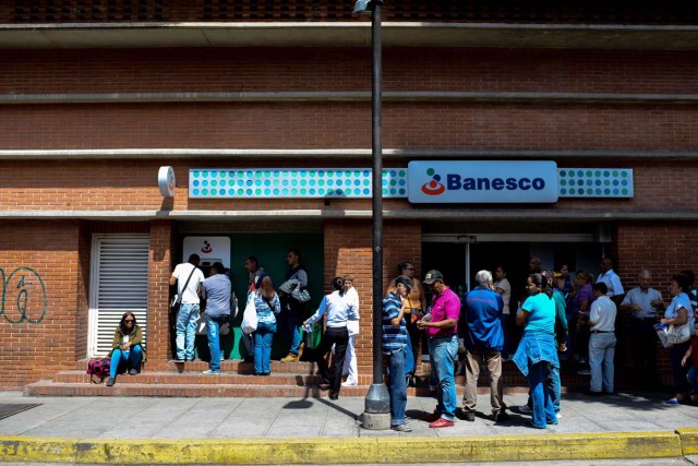 People queue to withdraw money from an ATM in Caracas on November 2, 2017. This week, Venezuelan President Nicolas Maduro introduced a new bank note of 100,000 Bolivars - five times the current largest denomination - and announced a 30 percent minimum wage hike. / AFP PHOTO / FEDERICO PARRA