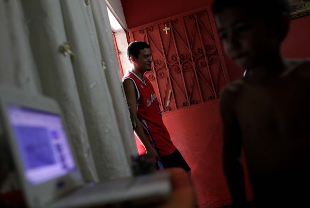 Willian Torres (L), stands in the doorway to his house on the outskirts of Caracas, Venezuela, October 14, 2017. Torres wagered money on "Los Animalitos" (or the Little Animals) betting game during the week, planning to go to the beach with his family with the prize money, but he didn't win. REUTERS/Ricardo Moraes SEARCH "MORAES GAMBLING" FOR THIS STORY. SEARCH "WIDER IMAGE" FOR ALL STORIES.
