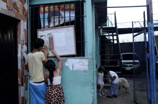 Children check the list for "Los Animalitos" (or the Little Animals) betting game on the outskirts of Caracas, Venezuela, October 6, 2017. REUTERS/Ricardo Moraes SEARCH "MORAES GAMBLING" FOR THIS STORY. SEARCH "WIDER IMAGE" FOR ALL STORIES.