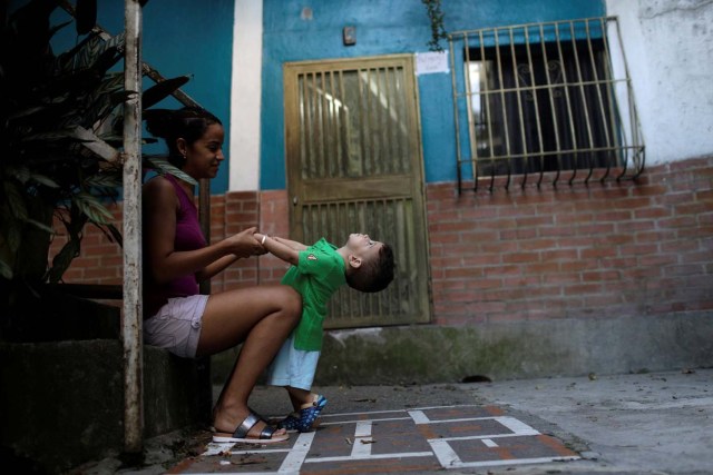 Veruska Torres plays with her son on the outskirts of Caracas, Venezuela, October 11, 2017. He is wearing a new t-shirt bought with prize money won on "Los Animalitos" (or the Little Animals) betting game. REUTERS/Ricardo Moraes SEARCH "MORAES GAMBLING" FOR THIS STORY. SEARCH "WIDER IMAGE" FOR ALL STORIES.