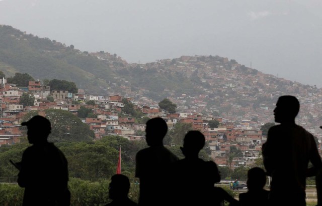 People watch a horse race, with a slum or "barrio" in the background, at La Rinconada Hippodrome, in Caracas, Venezuela, September 30, 2017. REUTERS/Ricardo Moraes SEARCH "MORAES GAMBLING" FOR THIS STORY. SEARCH "WIDER IMAGE" FOR ALL STORIES.