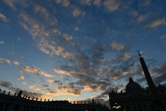 St Peter's basilica and the statues on the top of the colonnade are silhouetted at sunset on December 7, 2017 in Vatican. / AFP PHOTO / Alberto PIZZOLI