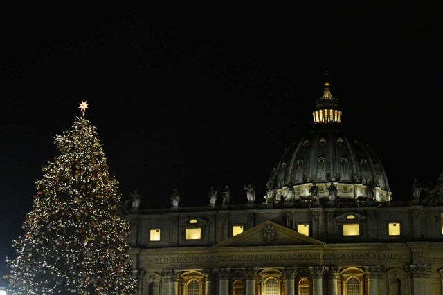 The christmas tree of St Peter's square is illuminated with St Peter's basilica in the background during the inauguration of the christmas crib on December 7, 2017 in Vatican. / AFP PHOTO / Alberto PIZZOLI