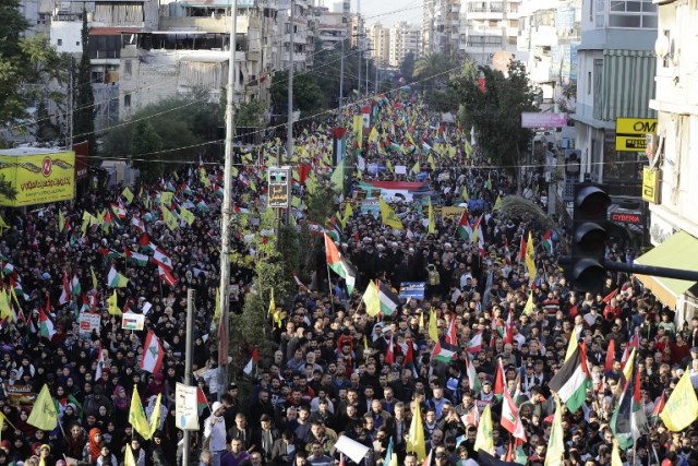 Supporters of Lebanon's Hezbollah Shiite movement wave national, Palestinian and Hezbollah flags during a massive rally in the Lebanese capital Beirut on December 11, 2017 in protest against the US president's controversial recognition of Jerusalem as Israel's capital. / AFP PHOTO / Joseph EID