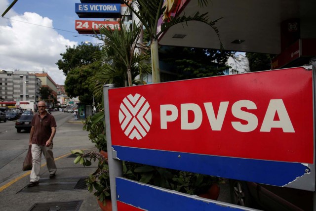 A man walks past the corporate logo of the state oil company PDVSA at a gas station in Caracas, Venezuela December 1, 2017. REUTERS/Marco Bello