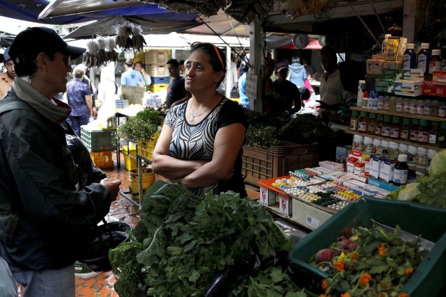 A vendor talks with a customer in her fruit and vegetables stall selling medicines at a market in Rubio, Venezuela December 5, 2017. Picture taken December 5, 2017. REUTERS/Carlos Eduardo Ramirez