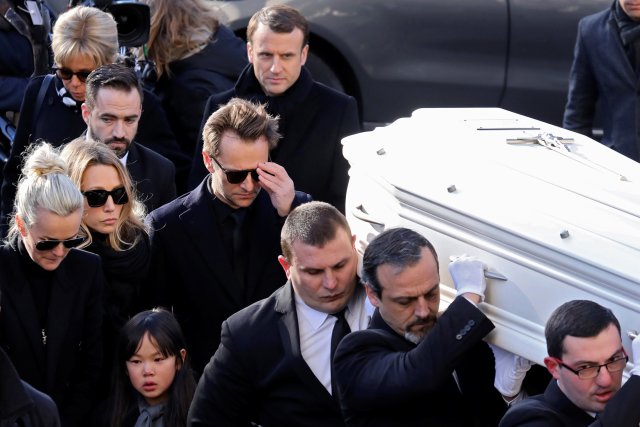The wife of late French singer Johnny Hallyday, Laeticia (center L), his daughter Laura Smet (2ndR, C), his son David Hallyday (3rdL, C), his daughter Joy, French President Emmanuel Macron (Top R) and his wife Brigitte (Top L) walk near the coffin outside at the Madeleine Church at the start of the funeral ceremony in Paris, France, December 9, 2017. REUTERS/Ludovic Marin/pool