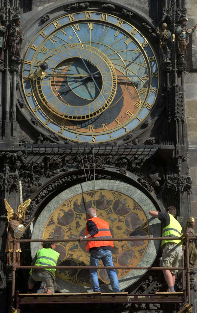 (FILES) This file photo taken on May 25, 2017 shows clockmaker Petr Skala (C) removing the calendar dial of Prague's medieval astronomical clock (Prazsky orloj), during the ongoing renovation of the Old Town Hall at the Old Town Square in Prague. The Prazsky orloj, the third-oldest astronomical clock in the world, will be dismantled from January 8, 2018, for a six-month renovation. / AFP PHOTO / Michal Cizek