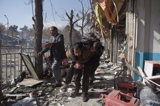 Afghan volunteers carry a body at the scene of a car bomb exploded in front of the old Ministry of Interior building in Kabul on January 27, 2018. An ambulance packed with explosives blew up in a crowded area of Kabul on January 27, killing at least 17 people and wounding 110 others, officials said, in an attack claimed by the Taliban. / AFP PHOTO / WAKIL KOHSAR