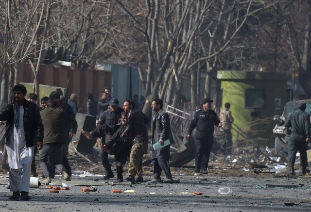 Afghan volunteers and policemen help wounded at the scene of a car bomb exploded in front of the old Interior Ministry building in Kabul on January 27, 2018. An ambulance packed with explosives blew up in a crowded area of Kabul on January 27, killing at least 17 people and wounding 110 others, officials said, in an attack claimed by the Taliban. / AFP PHOTO / WAKIL KOHSAR