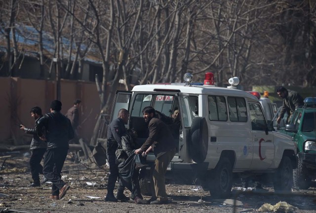 Afghan volunteers and policemen carry injured men on an ambulance at the scene of a car bomb exploded in front of the old Ministry of Interior building in Kabul on January 27, 2018. An ambulance packed with explosives blew up in a crowded area of Kabul on January 27, killing at least 17 people and wounding 110 others, officials said, in an attack claimed by the Taliban. / AFP PHOTO / WAKIL KOHSAR