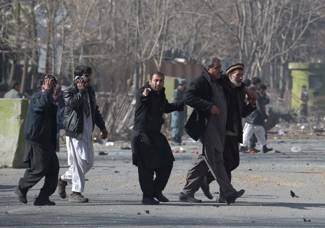 Afghan volunteers help an injured men at the scene of a car bomb exploded in front of the old Ministry of Interior building in Kabul on January 27, 2018. An ambulance packed with explosives blew up in a crowded area of Kabul on January 27, killing at least 17 people and wounding 110 others, officials said, in an attack claimed by the Taliban. / AFP PHOTO / WAKIL KOHSAR