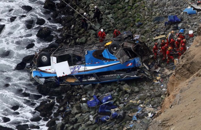 Rescue workers work at the scene after a bus crashed with a truck and careened off a cliff along a sharply curving highway north of Lima, Peru, January 3, 2018. REUTERS/Guadalupe Pardo TPX IMAGES OF THE DAY