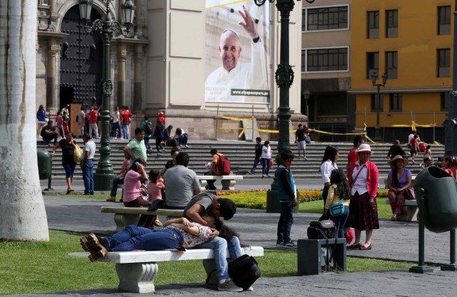  La gente descansa cerca de la Catedral de Lima con una pancarta del Papa Francisco antes de su visita al Perú del 18 al 21 de enero, en Lima, Perú, el 3 de enero de 2018. REUTERS / Mariana Bazo