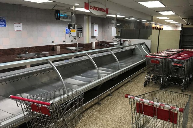 Stacked shopping carts are seen next to empty refrigerators at the deli area at a supermarket in Caracas, Venezuela January 10, 2018. REUTERS/Marco Bello