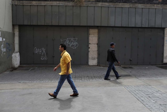 People walk past reinforced security gates at a store in downtown Caracas, Venezuela January 16, 2018. Picture taken January 16, 2018. REUTERS/Marco Bello