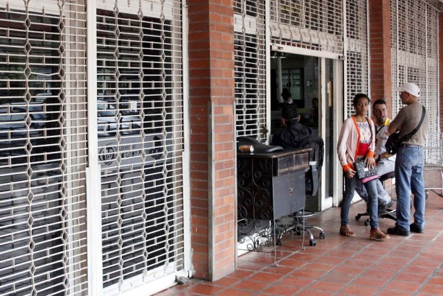 Una mujer sale de un supermercado con las rejas parcialmente cerradas como precaución contra disturbios o saqueos, en San Cristóbal, Venezuela, 16 de enero de 2018. REUTERS/Carlos Eduardo Ramirez