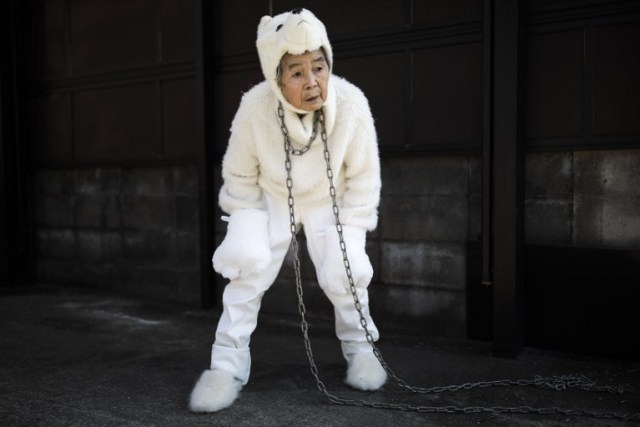 In this picture taken on January 16, 2018, Kimiko Nishimoto, dressed in a dog costume, gestures during a self photoshoot outside her house in the western Japanese city of Kumamoto. The madcap Japanese great-grandmother armed with a camera and an appetite for mischief has shot to fame for taking side-splitting selfies -- many of which appear to put her in harm's way. / AFP PHOTO / Behrouz MEHRI / TO GO WITH Japan-lifestyle-photography-offbeat-senior-citizens,FEATURE by Alistair HIMMER