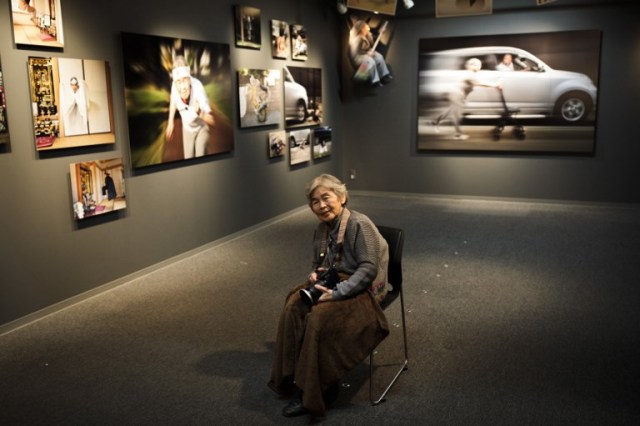 In this picture taken on December 14, 2017, Kimiko Nishimoto poses with a camera on the opening day of her photo exhibition in Tokyo. The madcap Japanese great-grandmother armed with a camera and an appetite for mischief has shot to fame for taking side-splitting selfies -- many of which appear to put her in harm's way. / AFP PHOTO / Behrouz MEHRI / TO GO WITH Japan-lifestyle-photography-offbeat-senior-citizens,FEATURE by Alistair HIMMER