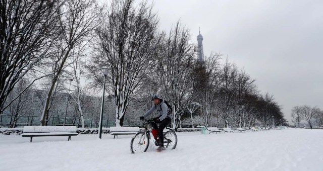 A man rides his bicycle on the snow-covered path near the Eiffel Tower in Paris, as winter weather with snow and freezing temperatures arrive in France, February 7, 2018. REUTERS/Gonzalo Fuentes