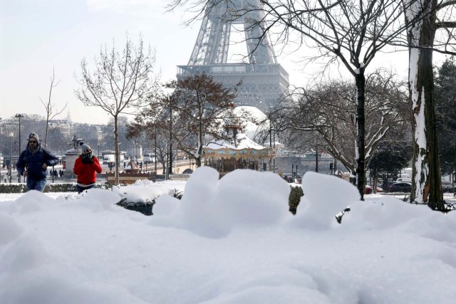 People walk on the snow-covered Trocadero gardens near the Eiffel Tower in Paris, as winter weather with snow and freezing temperatures arrive in France, February 8, 2018.   REUTERS/Charles Platiau