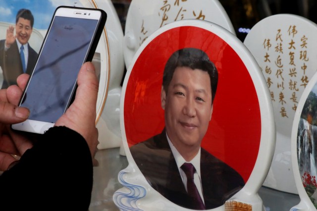 Un hombre toma una foto de unos platos de recuerdo con la imagen del presidente chino Xi Jinping en una tienda de la plaza de Tiananmen, Beijing, China, 26 de febrero de 2018. REUTERS/Thomas Peter