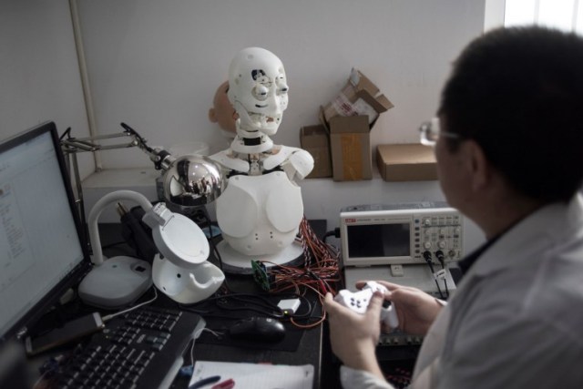 This photo taken on February 1, 2018 shows an engineer adjusting facial expressions on a robot in a lab of a doll factory of EXDOLL, a firm based in the northeastern Chinese port city of Dalian. With China facing a massive gender gap and a greying population, a company wants to hook up lonely men and retirees with a new kind of companion: "Smart" sex dolls that can talk, play music and turn on dishwashers. / AFP PHOTO / FRED DUFOUR / TO GO WITH China-sex-lifestyle, FOCUS by Joanna CHIU
