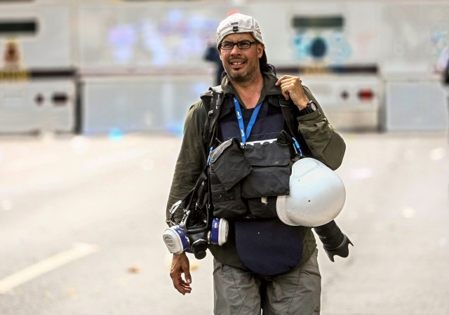 (FILES) In this file photo taken on May 06, 2017 The Venezuelan AFP photographer Ronaldo Schemidt is seen during coverage of a opposition protest in Caracas. A searing image of a Venezuelan protestor who caught fire during clashes with riot police has won AFP photographer Ronaldo Schemidt a nomination for the 2018 World Press Photo award. The Mexico-based snapper for Agence France-Presse is among six photographers, chosen from more than 4,500 hopefuls, to be nominated for the prestigious annual prize, the World Press Photo Foundation in Amsterdam revealed on February 14, 2018. / AFP PHOTO / Cristian HERNANDEZ