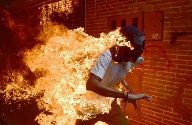 (FILES) In this file photo taken on May 03, 2017 A demonstrator catches fire during clashes with riot police within a protest against Venezuelan President Nicolas Maduro. A searing image of a Venezuelan protestor who caught fire during clashes with riot police has won AFP photographer Ronaldo Schemidt a nomination for the 2018 World Press Photo award. The Mexico-based snapper for Agence France-Presse is among six photographers, chosen from more than 4,500 hopefuls, to be nominated for the prestigious annual prize, the World Press Photo Foundation in Amsterdam revealed on February 14, 2018. / AFP PHOTO / RONALDO SCHEMIDT