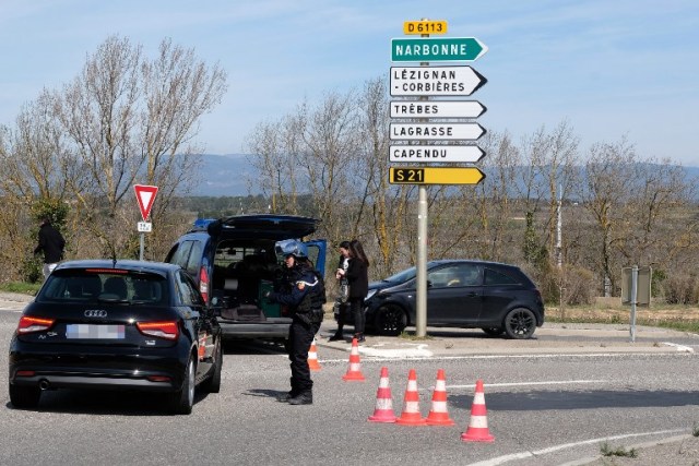 French gendarmes block the access to Trebes, where a man took hostages at a supermarket on March 23, 2018 in Trebes, southwest France.   At least one person was feared dead after a gunman claiming allegiance to the Islamic State group fired shots in a hostage-taking at a supermarket in southwest France, police said. / AFP PHOTO / ERIC CABANIS