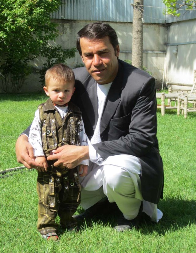 This photo taken on May 9, 2013 shows Agence France-Presse (AFP) photographer Shah Marai posing for a picture with one of his young sons, in the garden of the AFP bureau in Kabul. Shah Marai, Agence France-Presse's chief photographer in Kabul, who was killed covering a suicide bombing on April 30, 2018, was a charismatic, courageous journalist who was dedicated to reporting on Afghanistan's wrenching conflict. / AFP PHOTO / Ben Sheppard