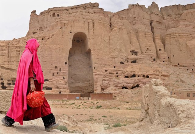 Una mujer afgana pasa frente a las ruinas de las antiguas estatuas de Buda en la ciudad de Bamiyán, el 1 de agosto de 2010. SHAH MARAI AFP