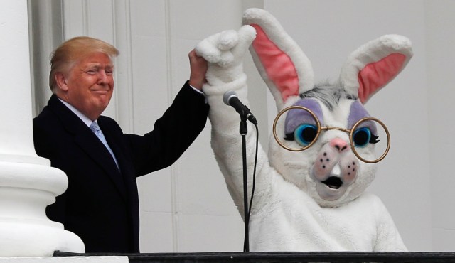 U.S. President Donald Trump raises the arm of the Easter Bunny as they appear together on the South Portico of the White House during the annual White House Easter Egg Roll on the South Lawn of the White House in Washington, U.S., April 2, 2018. REUTERS/Carlos Barria