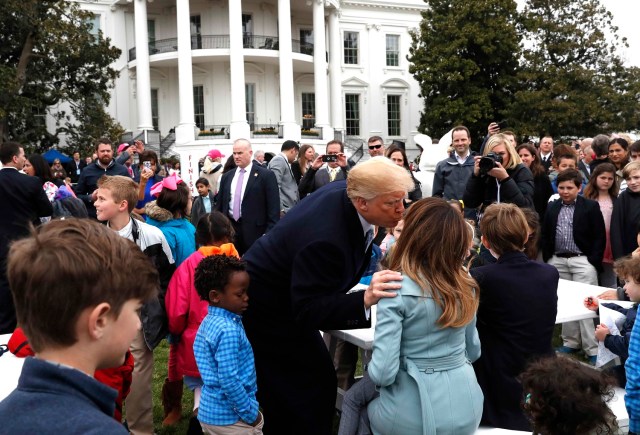 U.S. President Donald Trump kisses first lady Melania Trump among children gathered for the annual White House Easter Egg Roll on the South Lawn of the White House in Washington, U.S., April 2, 2018. REUTERS/Leah Millis