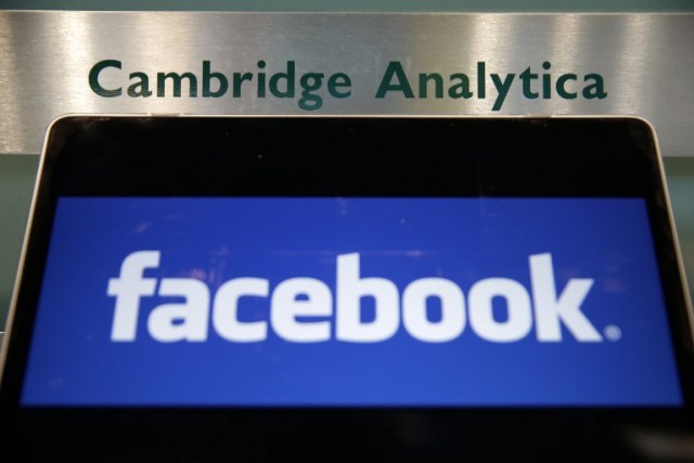 (FILES) In this file photo taken on March 21, 2018 A laptop showing the Facebook logo is held alongside a Cambridge Analytica sign at the entrance to the building housing the offices of Cambridge Analytica, in central London. Cambridge Analytica, the UK marketing analytics firm at the heart of the Facebook data scandal, announced on May 2, 2018, it was "immediately ceasing all operations" and filing for insolvency in Britain and the United States. "It has been determined that it is no longer viable to continue operating the business," the company, accused of misusing tens of millions of Facebook users' data, said in a statement. / AFP PHOTO / Daniel LEAL-OLIVAS
