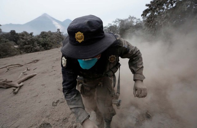 Un oficial de policía tropieza mientras huye después de que el volcán Fuego arrojara un nuevo flujo piroclástico en la comunidad de San Miguel Los Lotes en Escuintla, Guatemala, el 4 de junio de 2018. REUTERS / Luis Echeverría